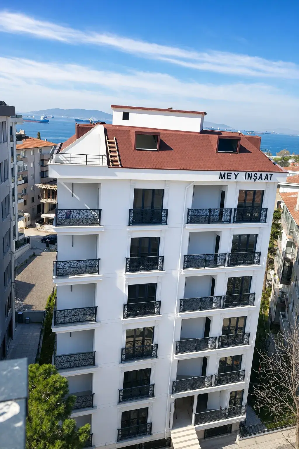 El Ele Apartmanı: beyaz cepheli, ferforje balkonlu bina; arkada Marmara Denizi ve gemiler